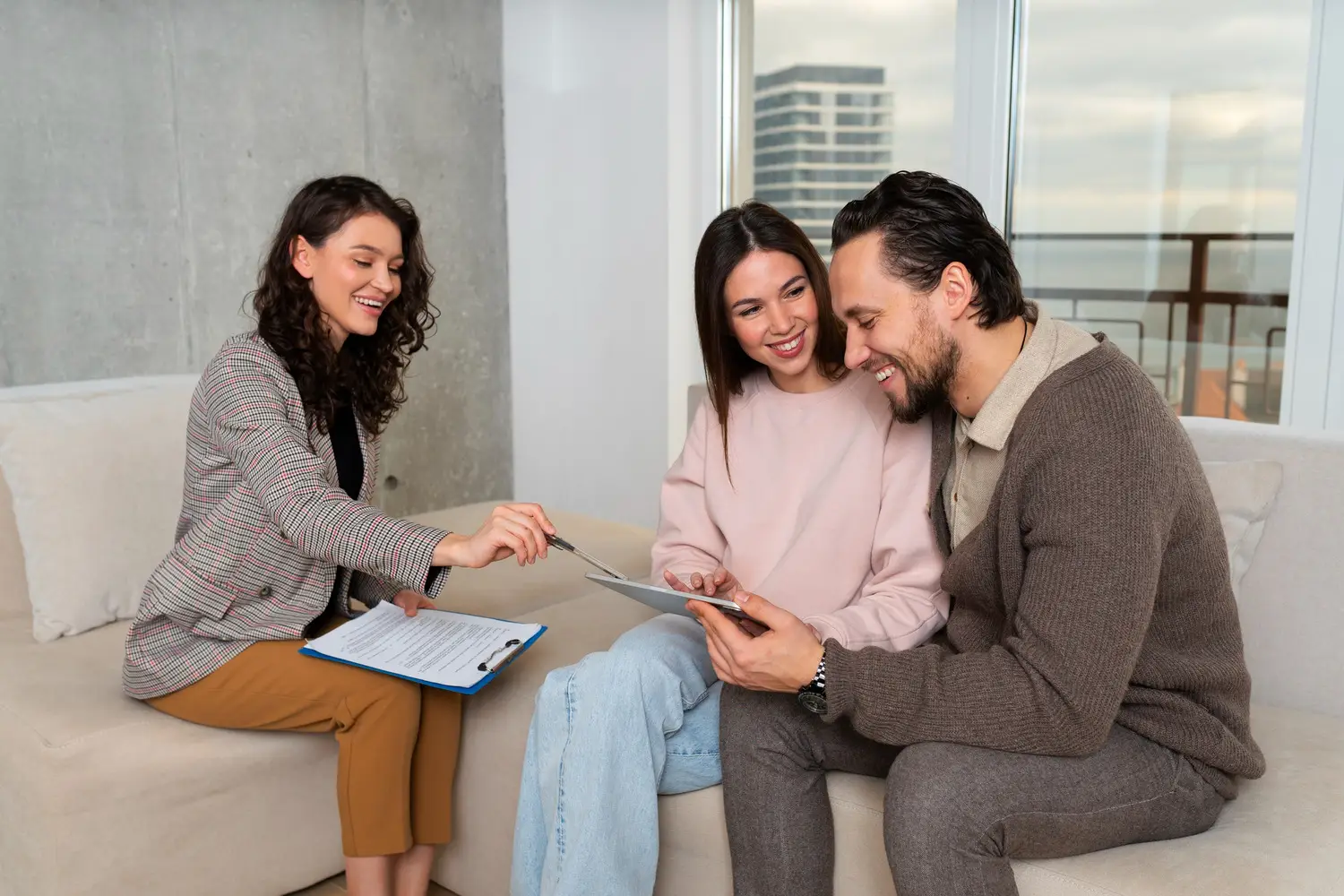 Three people having a meeting with documents and a tablet in a bright room.